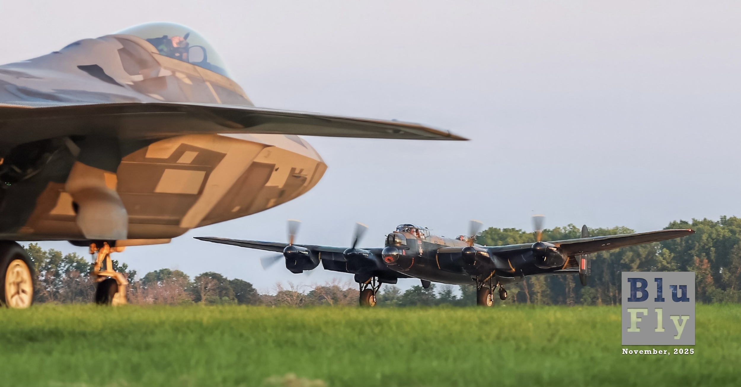 Avro Lancaster FM213, otherwise known as 'Vera' based on the squadron code « VRA », is in the process of taking off or landing at AirVenture (otherwise known as Oshkosh) in July of 2024. The aircraft is shot from ground level and at a distance. The Lancaster is moving toward and to the left of the camera position. The tailwheel is up, indicating that the aircraft is moving at considerable speed. On the left side of the frame, the forward part of the fuselage and the right wing of an F-35 are visible. It is slightly out of focus, which emphasises the Lancaster as the main subject of the photo. The F-35 has 'pixelated' camouflage in varying shades of light grey. In the foreground, the green grass adjacent to the runway is visible. A line of trees is visible beyond the two aircraft. The sky above is hazy blue, and the light is that of either sunrise or sunset. Superimposed on the bottom right corner of the photo is a grey, BluFly logo consisting of the words « Blu » on one line and then « Fly » on the next line. Both words are contained within a grey box. The former is shaded blue, and the latter is shaded white. The logo letters are ‘see-through’, such that elements of the photo can be seen through them. Below the logo are the words « November, 2025 » in a similar typeface in white. (📸 Cheryl Goodwin | Good 2 Go Photography. All rights reserved.)