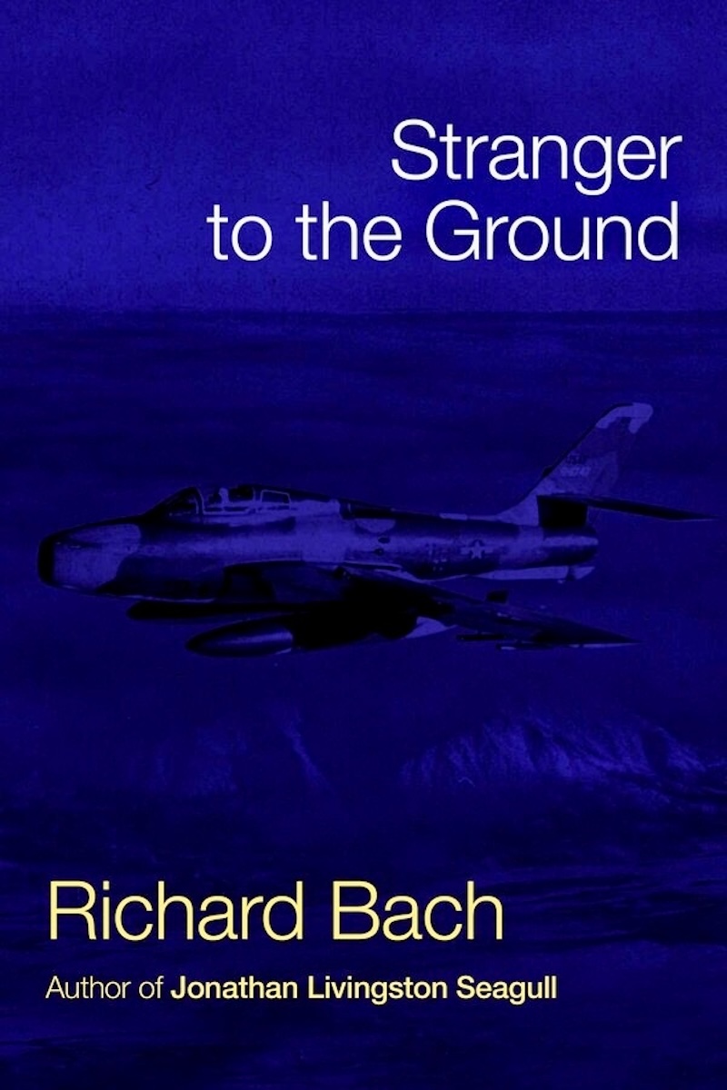 The cover of the book 'Stranger to the Ground' by Richard Bach. It is primarily blue with a very dim, difficult-to-discern image of some sort of jet fighter aircraft. (📸 Simon & Schuster, LLC)