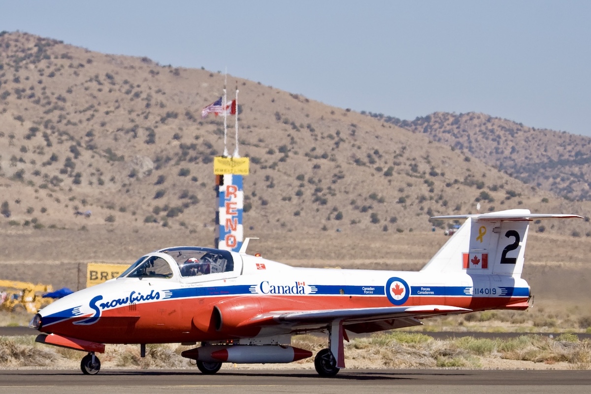 One of the RCAF Snowbirds taxies by one of the turn pylons at the Reno Air Races. The word RENO is painted on the pylon.