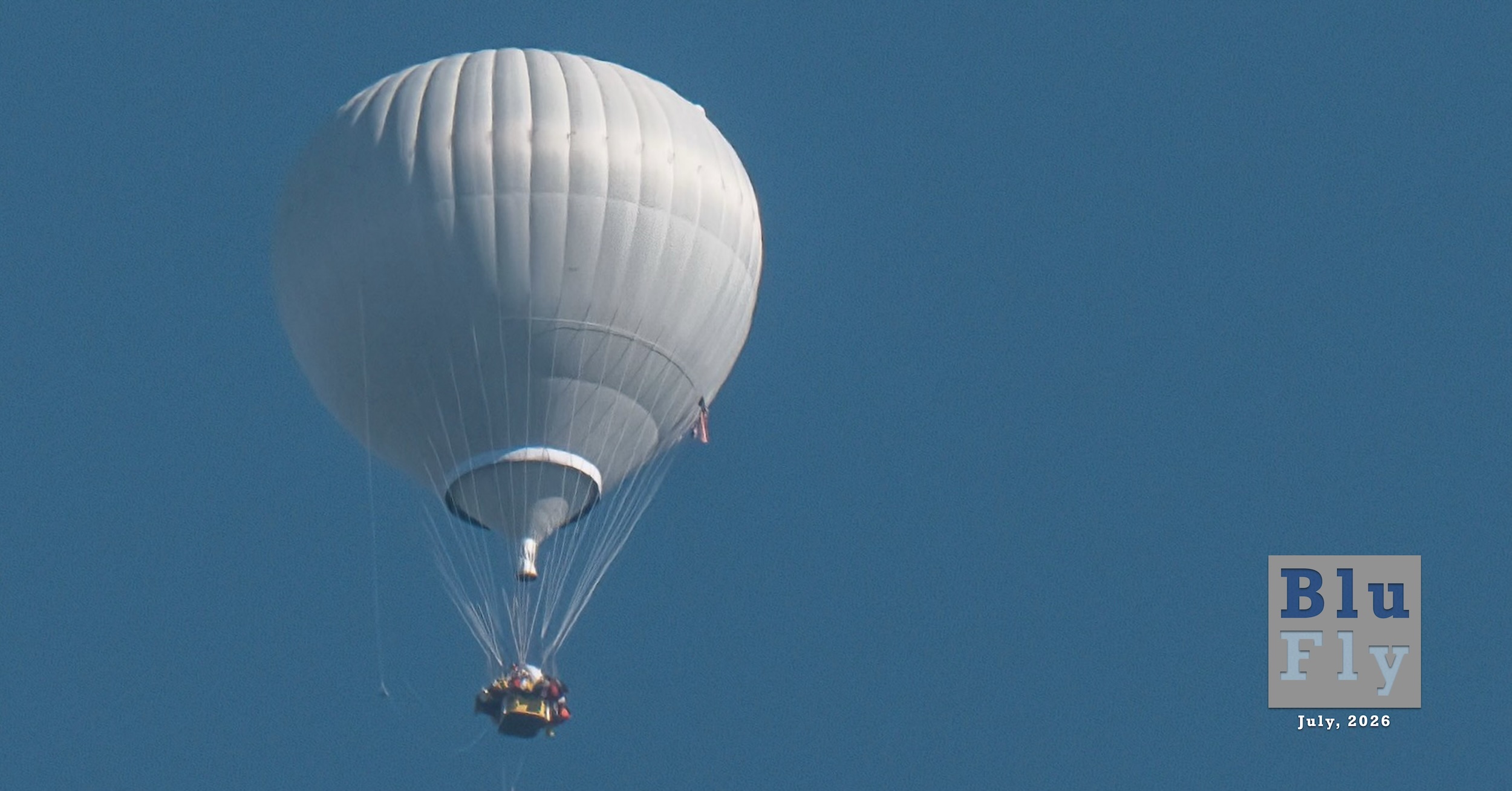 A white gas balloon floats in an entirely blue sky; no clouds can be seen. It is offset to the left in the frame. (📸 Kris Tynski)