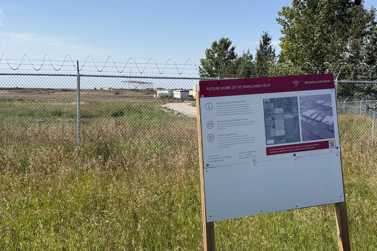 A sign with the title Future Home of De Havilland Field, with some illustrations and more detailed explanations. A construction site is visible beyond it.